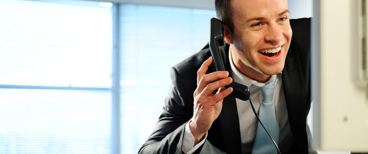 Foto de um homem usando um telefone VoIP em seu escritório.